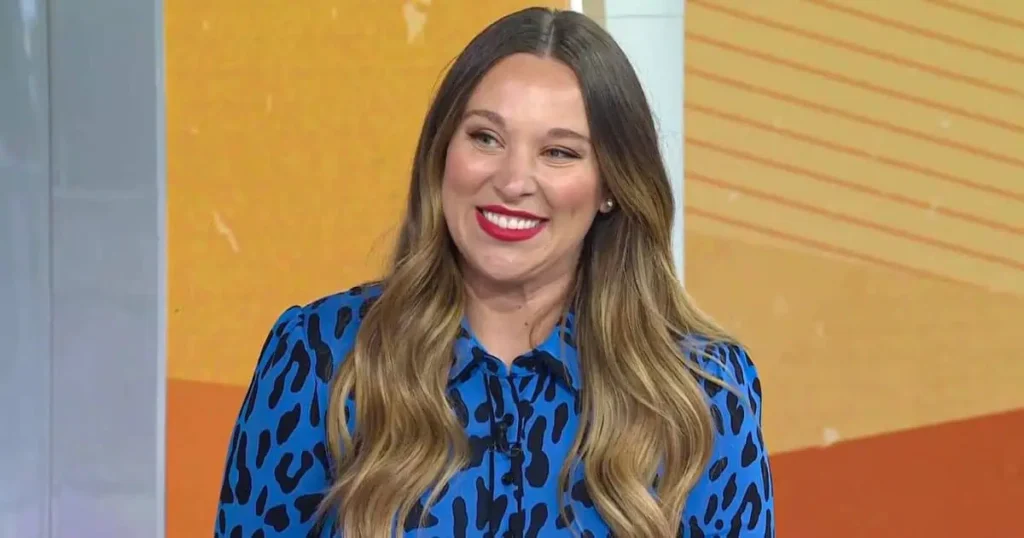 A woman in a blue and black dress smiles, embodying the spirit of philanthropy and social impact through her joyful demeanor.