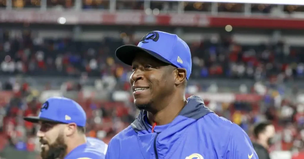 A man in a blue hat and jacket smiles, reflecting the positivity in Raheem Morris’s career achievements.