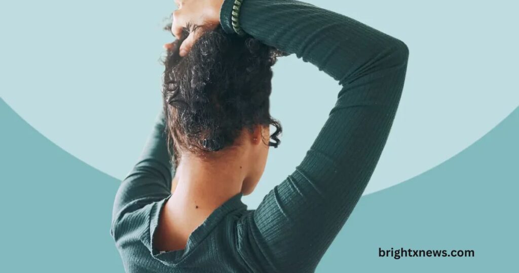 A woman with curly hair holds her hair up, contemplating if does-native-shampoo-have-side-effects for her hair type.